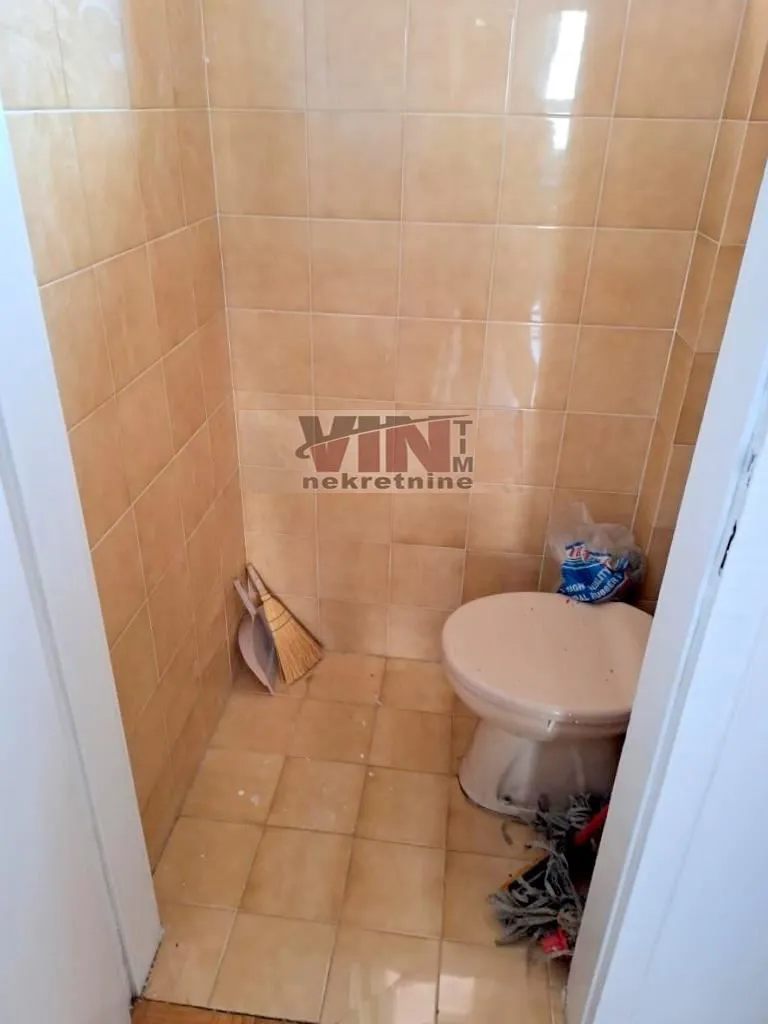 Manje kupatilo obloženo keramičkim pločicama sa toaletnom šoljom.