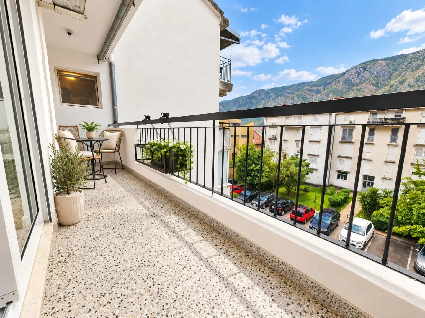 Namtješten balkon sa garniturom za sjedenje i pogledom na naselje i planine.