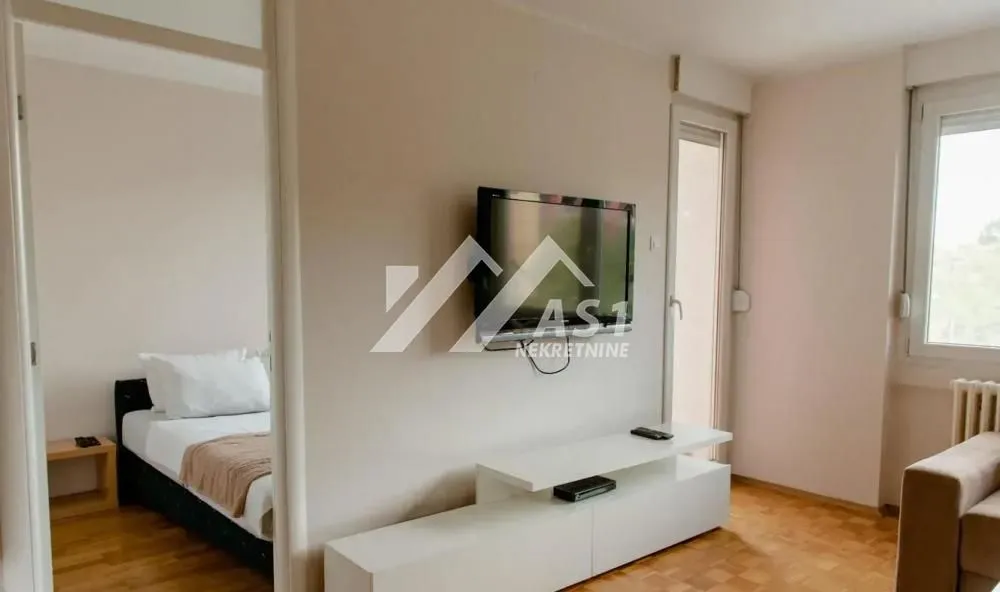 Dnevna soba sa televizorom i pogledom na spavaću sobu kroz vrata.
