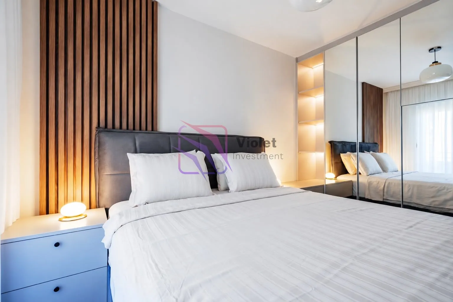 Modern bedroom with a double bed, wooden wall panel, and a large mirror.