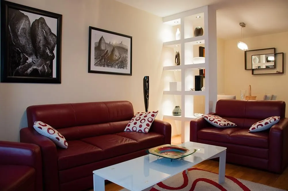 Bright living room featuring red leather sofas and decorative shelving.