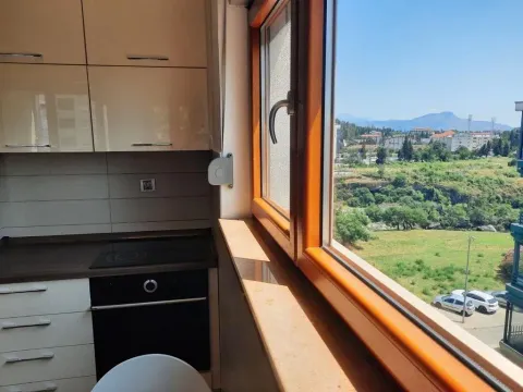 Small kitchen with built-in oven and cooktop next to a window with a view. - image 4