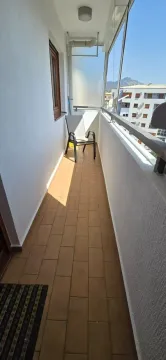 Zastakljeni balkon sa stolicom i pogledom na okolne zgrade. - image 11
