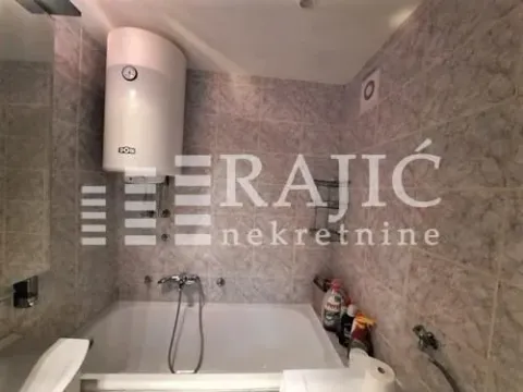 Smaller bathroom with a bathtub and a wall-mounted water heater. - image 7