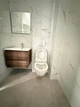 Modern bathroom with a sink, mirror, and toilet bowl clad in marble tiles. - image 5