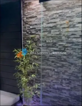 Detalj enterijera sa dekorativnim kamenim zidom i biljkom. - image 13