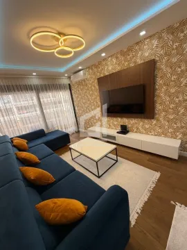 Modern living room with a blue sectional sofa, TV, and decorative wallpaper. - image 5