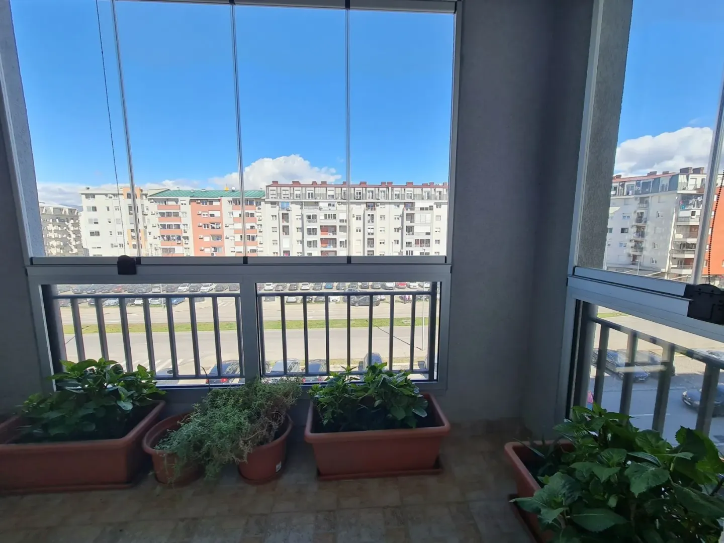 Glazed terrace with potted plants and a view of the surrounding buildings.
