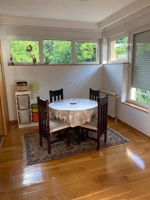 Dining area with a round table and chairs by the windows.