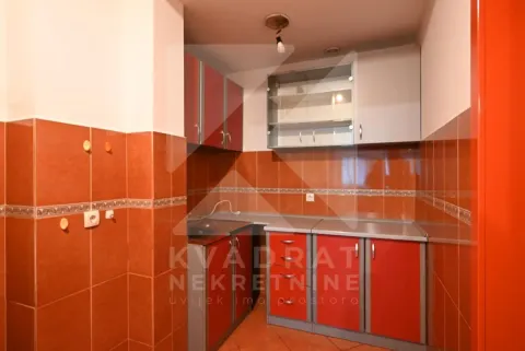 Small kitchen with red cabinets and warm-toned wall tiles. - image 9