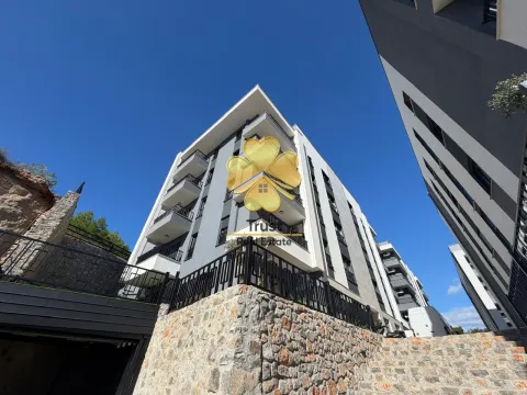 Exterior of a modern residential building with terraces and a stone retaining wall. - image 13