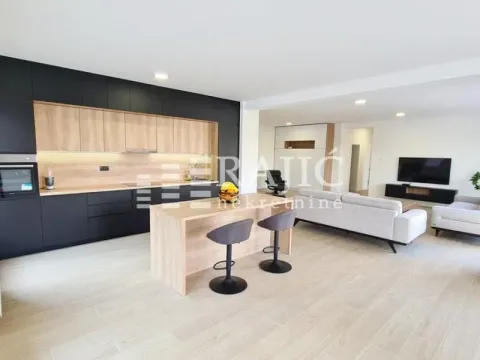 Modern kitchen with a breakfast bar and open-plan living area. - image 8