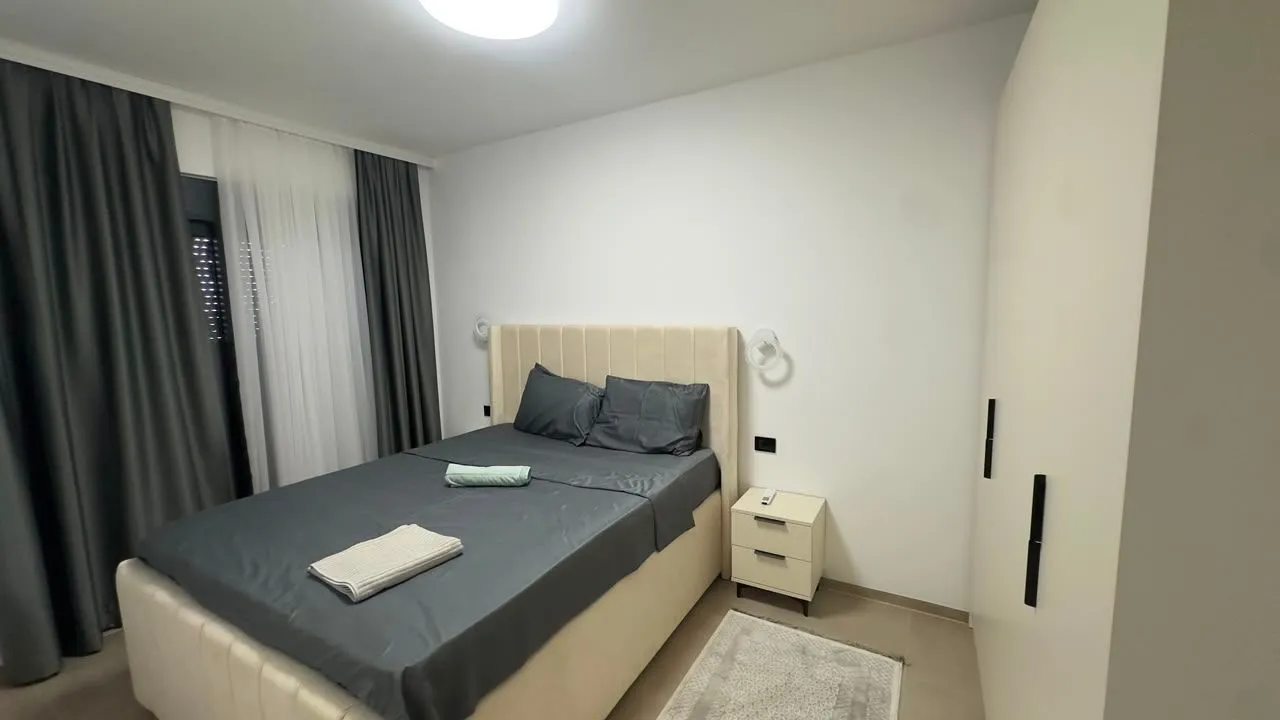 Spavaća soba sa bračnim krevetom, garderoberom i prozorom sa zavjesama.