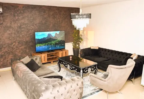 Spacious living room with seating set, TV, and decorative chandelier. - image 6