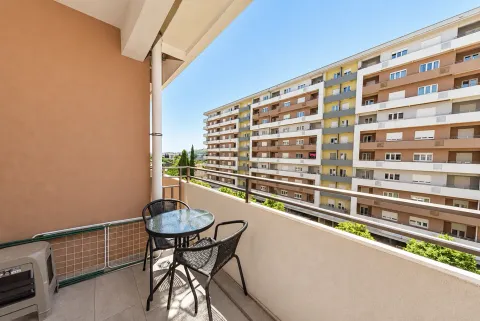 Furnished balcony with a table, chairs, and a view of the neighboring building. - image 5