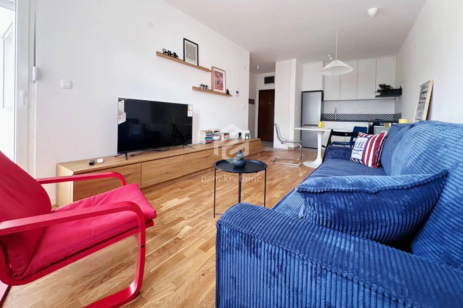 Living room with a sofa, TV, and dining area in the background.
