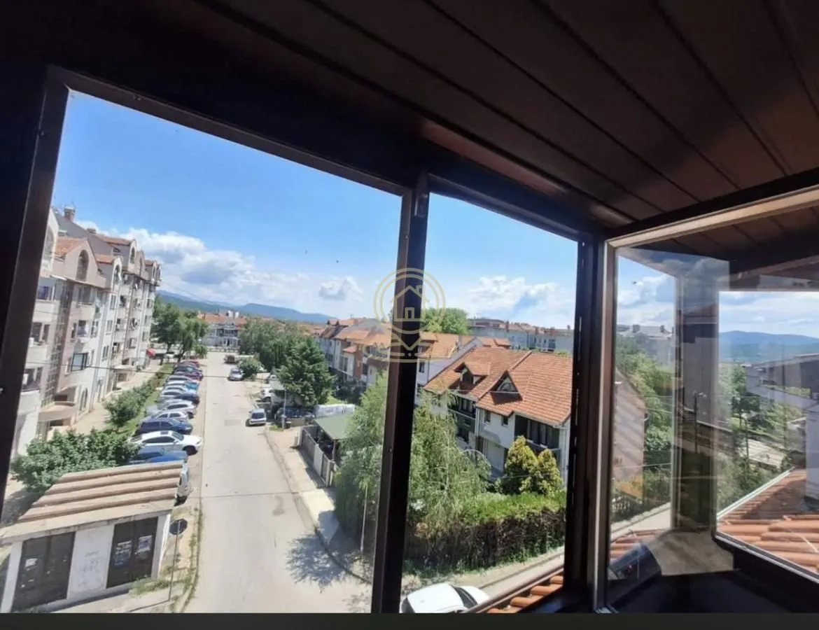 Zastakljena terasa sa koje se pruža pogled na gradsku ulicu i okolne zgrade.