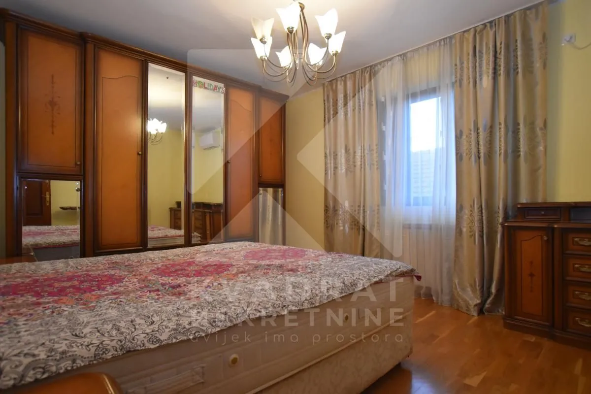 Furnished bedroom with a large double bed and a wooden wardrobe.