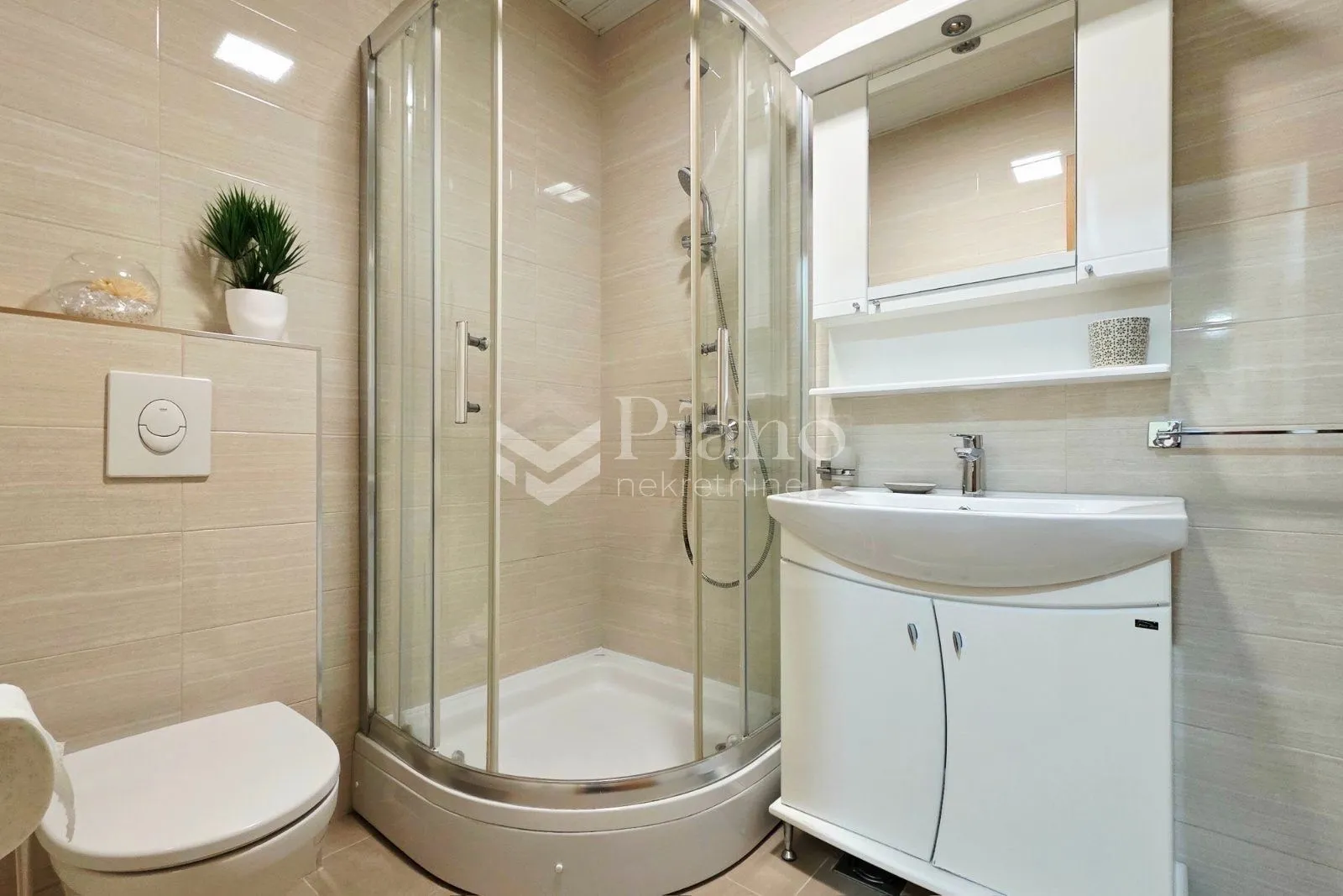 A compactly equipped bathroom with a shower cabin, washbasin, and toilet.