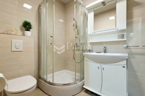 A compactly equipped bathroom with a shower cabin, washbasin, and toilet. - image 9
