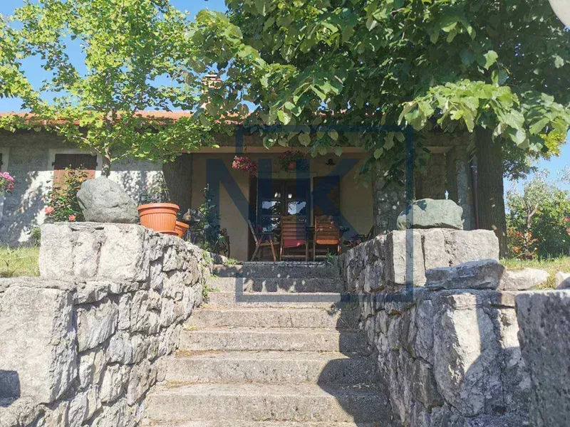 Kameno stepenište koje vodi do ulaza u kuću okruženu zelenilom.