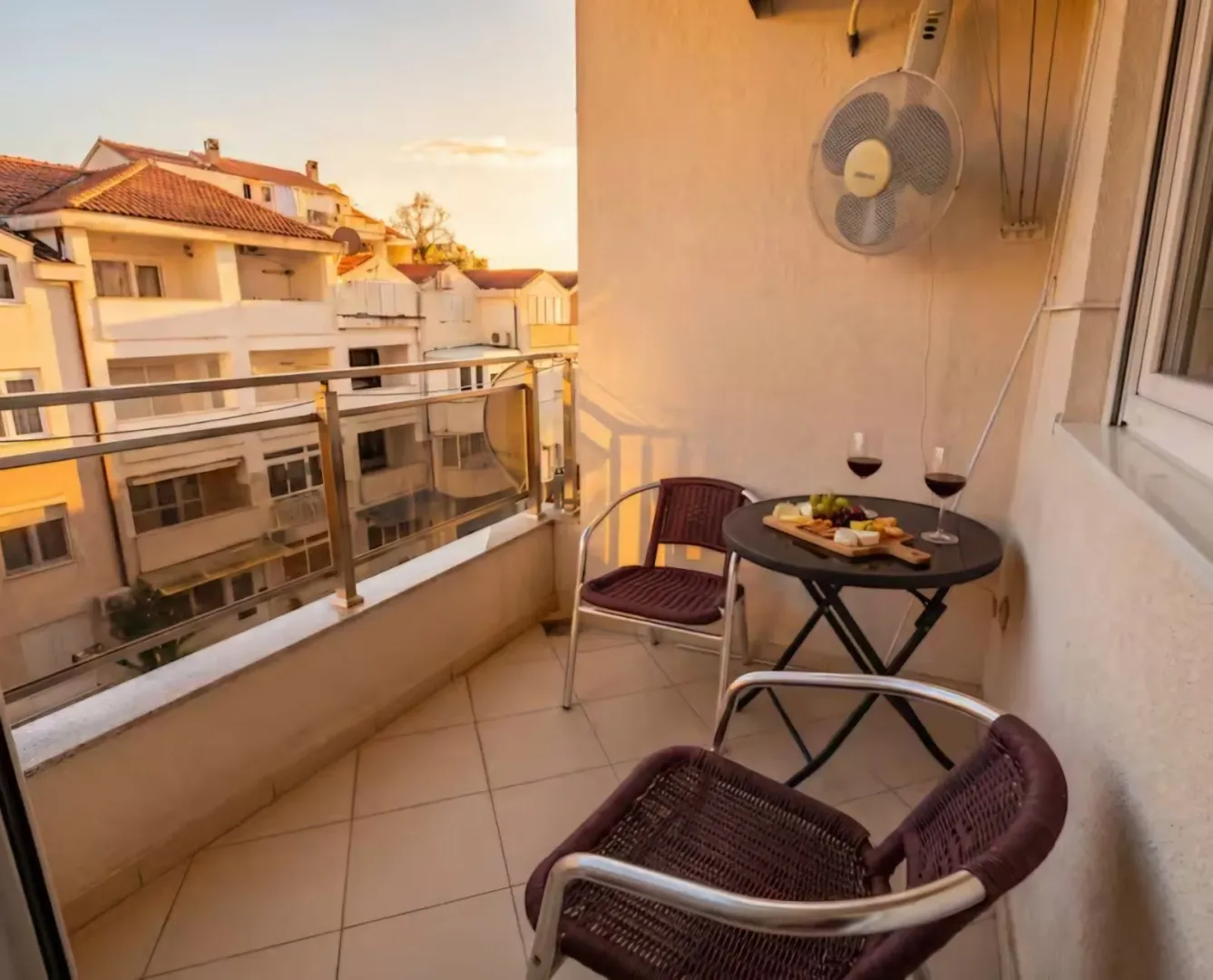 Namješten balkon sa stolom, stolicama i pogledom na naselje.