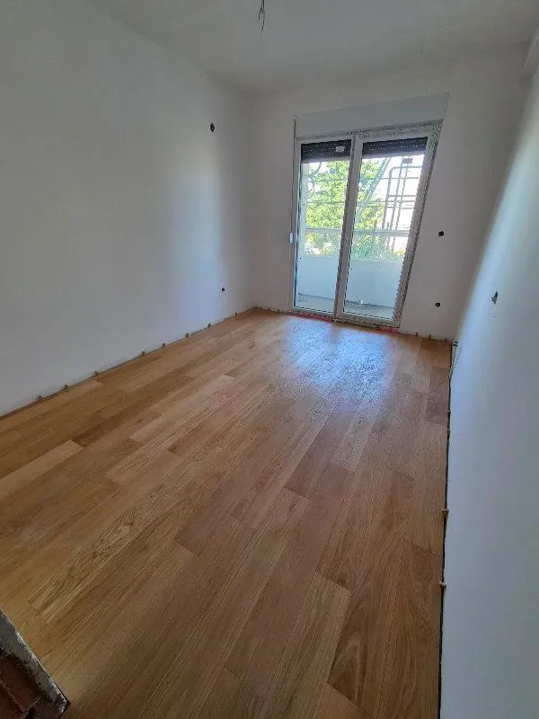Empty room with installed hardwood flooring and access to the balcony.