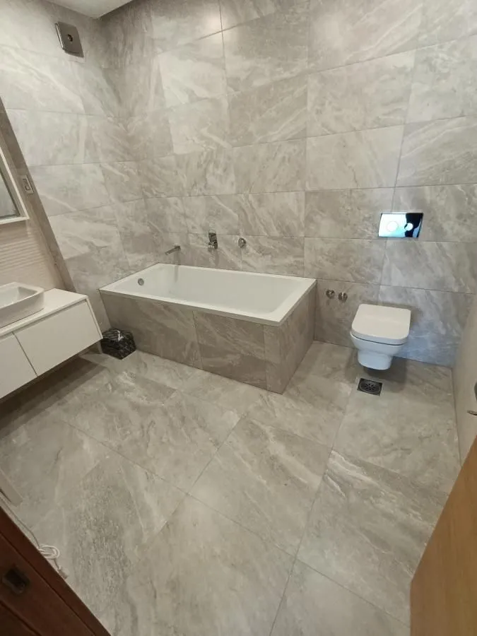 Bathroom equipped with a bathtub, wall-mounted toilet, and vanity with a sink.