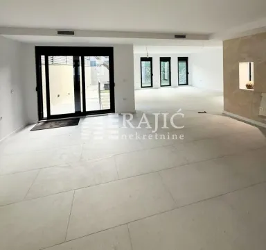 Prostrana svetla prostorija u enterijeru sa keramičkim pločicama na podu i velikim staklenim otvorima. - image 11
