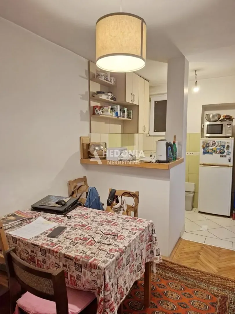 Manja kuhinja sa trpezarijskim stolom i kuhinjskim elementima.