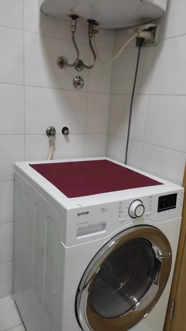 Kupatilo sa veš mašinom i pločicama na zidu.