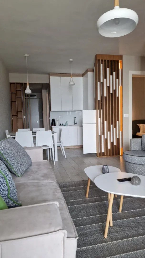 Living room with a sofa, dining area, and kitchen in the background.