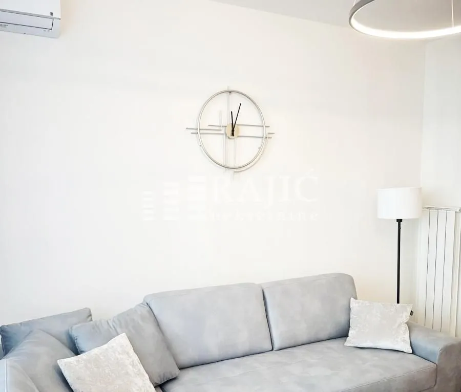 Living room with a grey sofa and a wall clock.