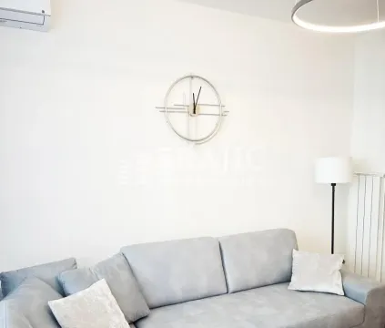 Living room with a grey sofa and a wall clock. - image 5