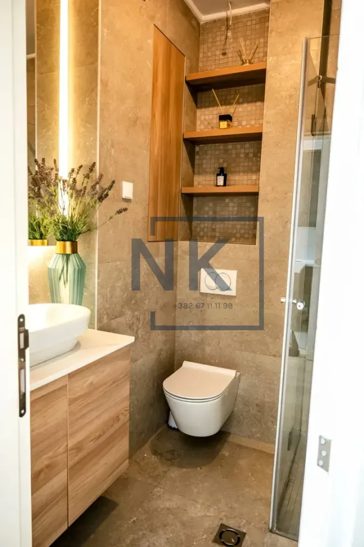 Moderne kupatilo sa umivaonikom, ugradnom WC šoljom i tuš kabinom.