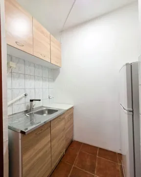 Small kitchen with wooden cabinets and a refrigerator. - image 7