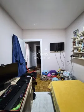 Manja spavaća soba sa krevetom, radnim stolom i televizorom na zidu. - image 6