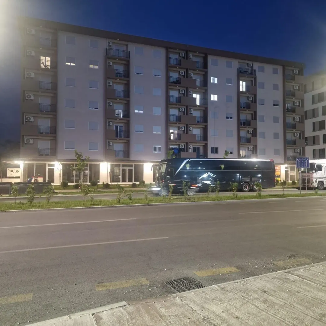 Exterior of an apartment building at night with a street in the foreground.