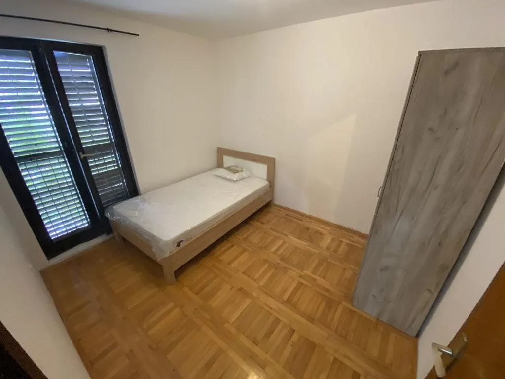 Small bedroom with a bed, wooden flooring, and a wardrobe.