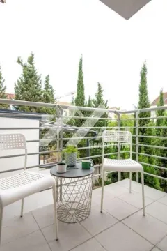Namješten balkon sa stolom, dvije stolice i pogledom na zelenilo. - image 10