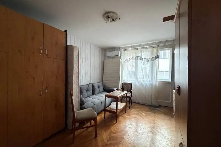 Dnevna soba sa garniturom za sedenje, ormarima i drvenim podom.