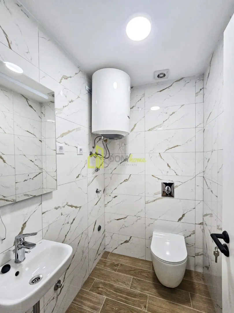 Manje kupatilo obloženo keramičkim pločicama sa umivaonikom, WC šoljom i bojlerom.