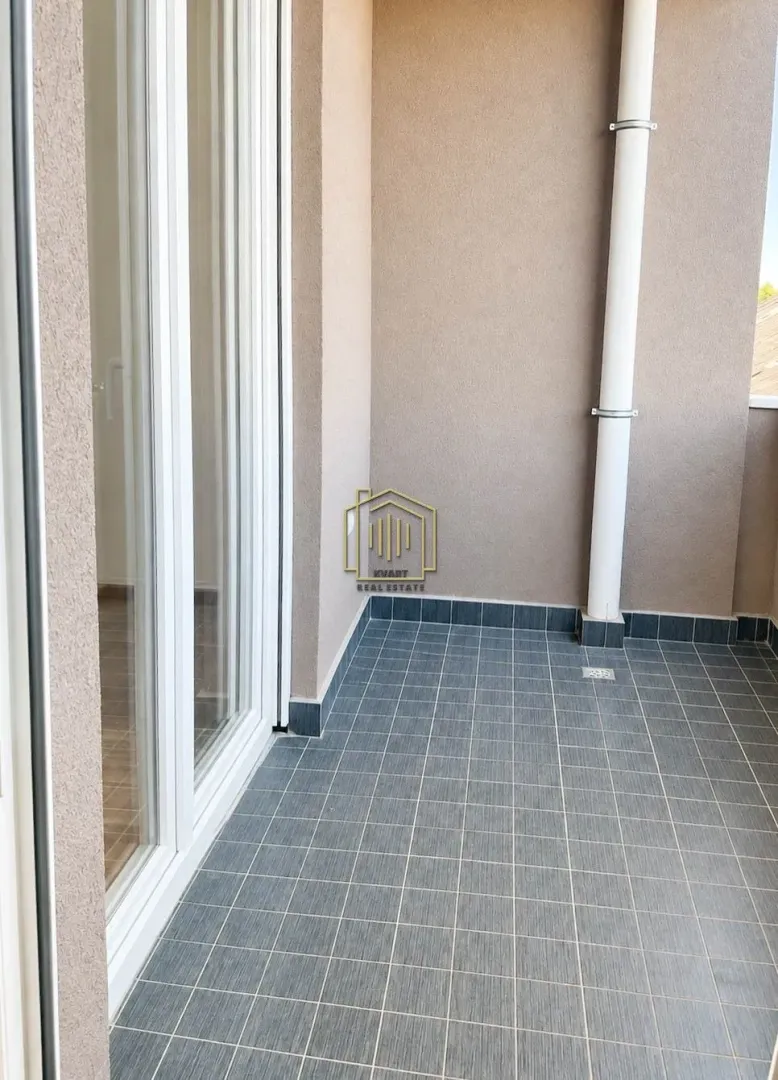 Nenamješten balkon sa pločicama na podu i balkonskim vratima.