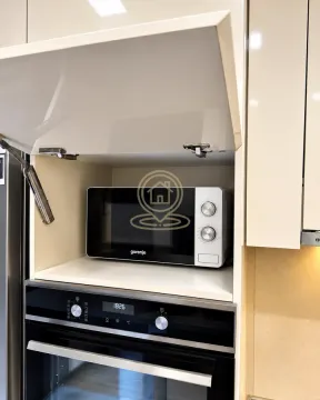 A microwave oven and built-in oven inside kitchen cabinets. - image 7