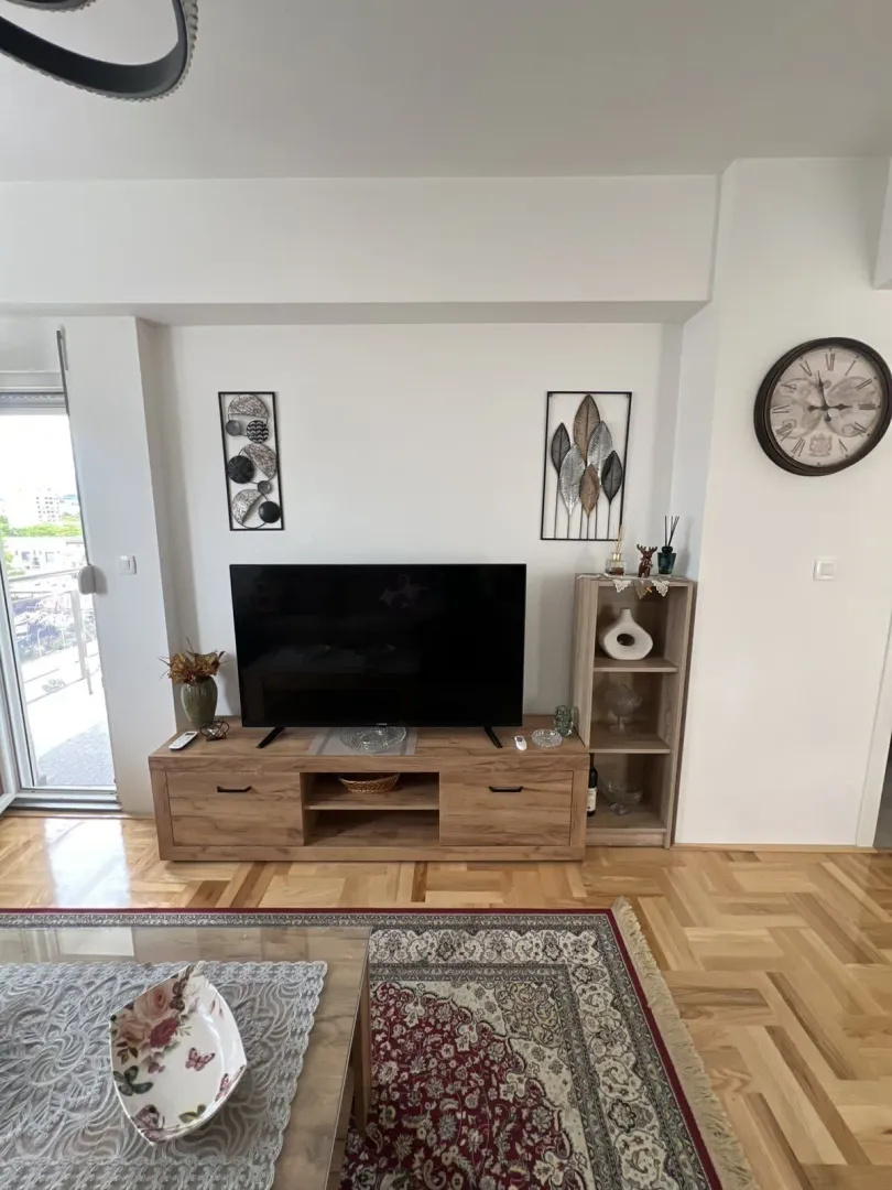 Bright living room featuring a wooden TV stand and parquet flooring.