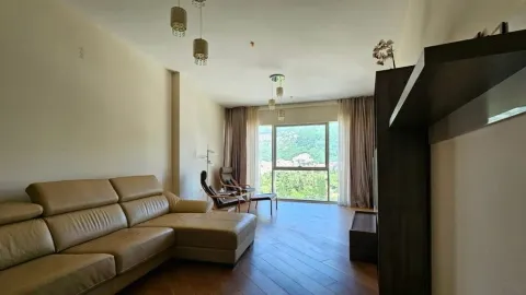 Living room with a sofa and a large window overlooking greenery. - image 2