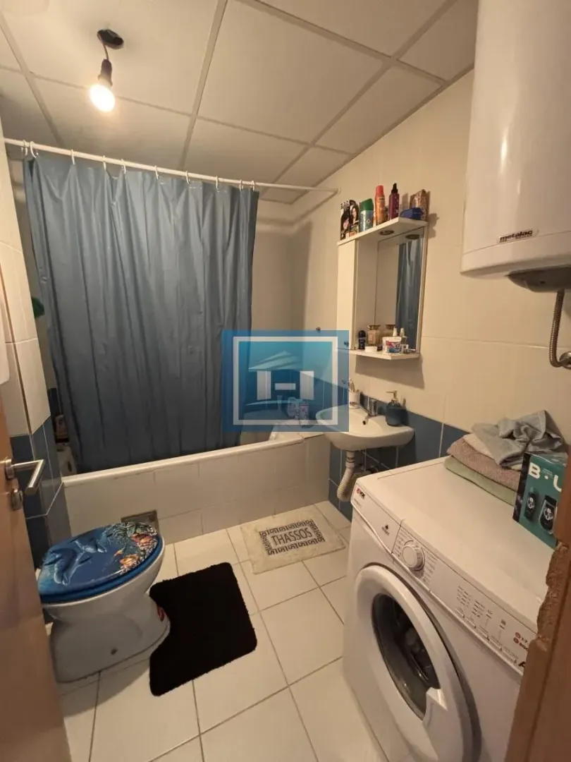 Manje kupatilo sa kadom, umivaonikom, WC šoljom i veš mašinom.