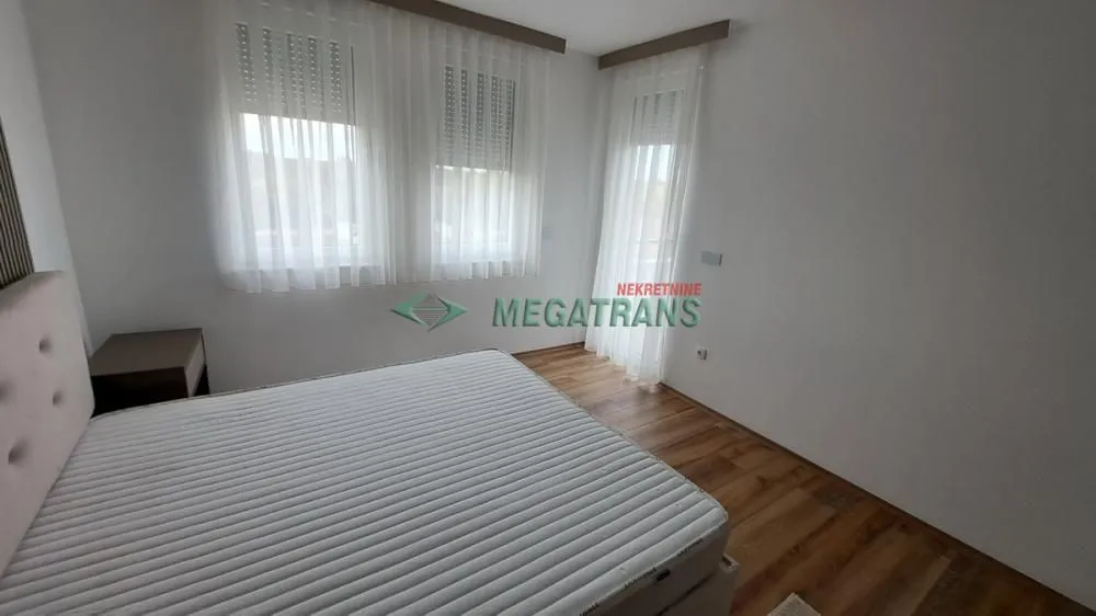 Svetla spavaća soba sa bračnim krevetom i prozorima.