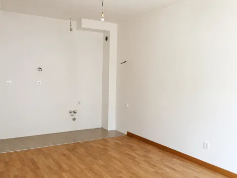 Prazna prostorija sa bijelim zidovima, drvenim podom i pripremljenim instalacijama. - image 4