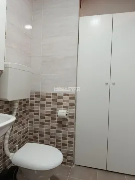Pogled na kupatilo sa WC šoljom, umivaonikom i belim ormarićem. - image 15